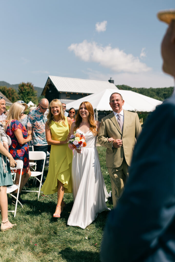 a bride walking down the aisle with her parents at a wedding ceremony