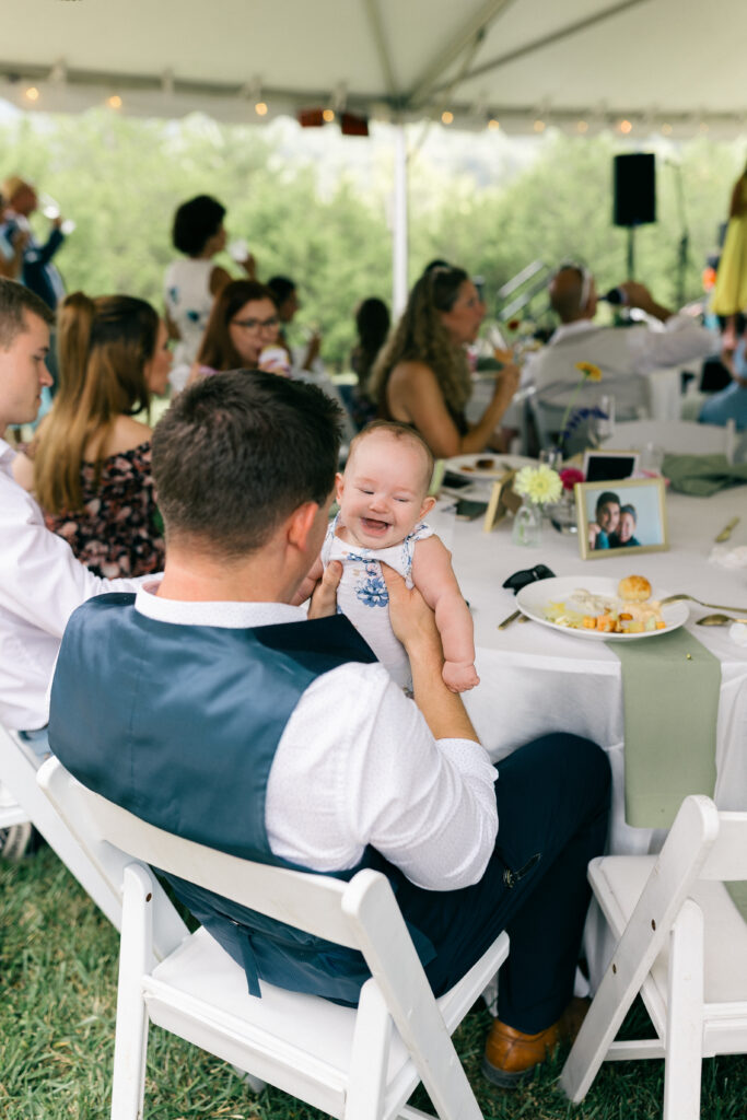 baby laughing in dad's arms at wedding reception