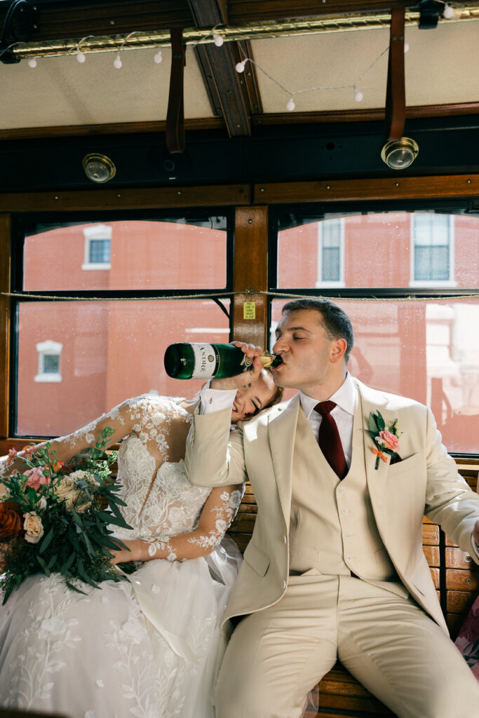bride leaning on groom while he drinks champagne