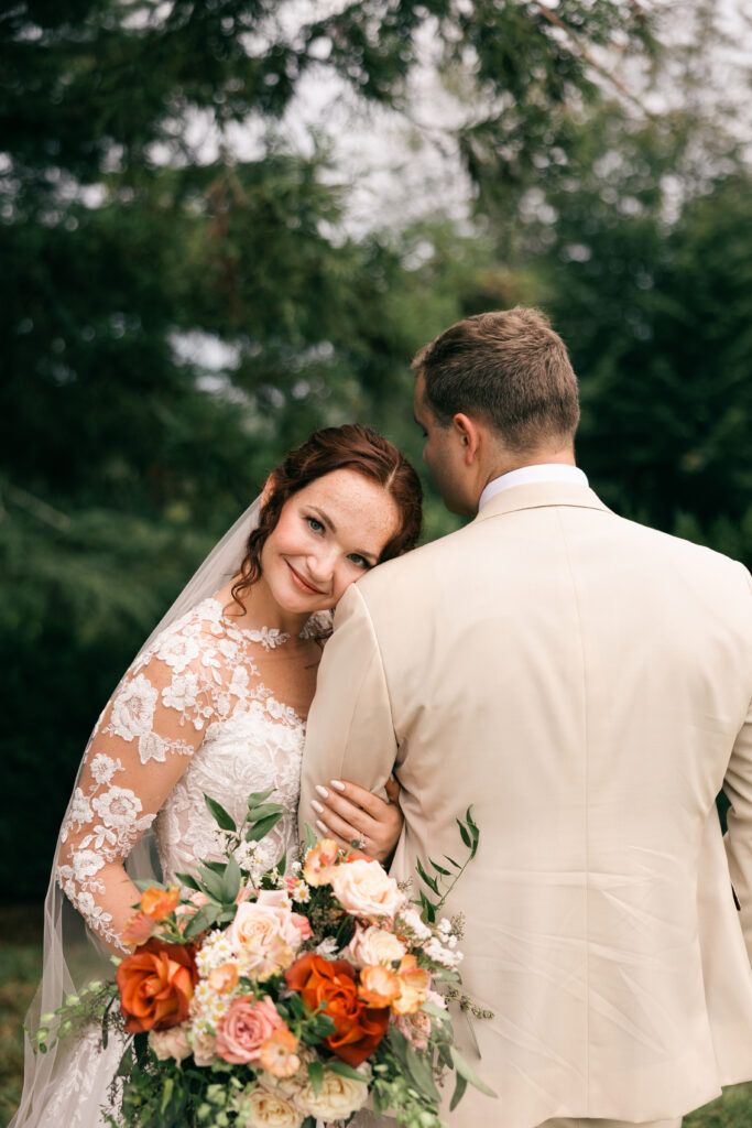 bride holding groom's arm while looking at camera